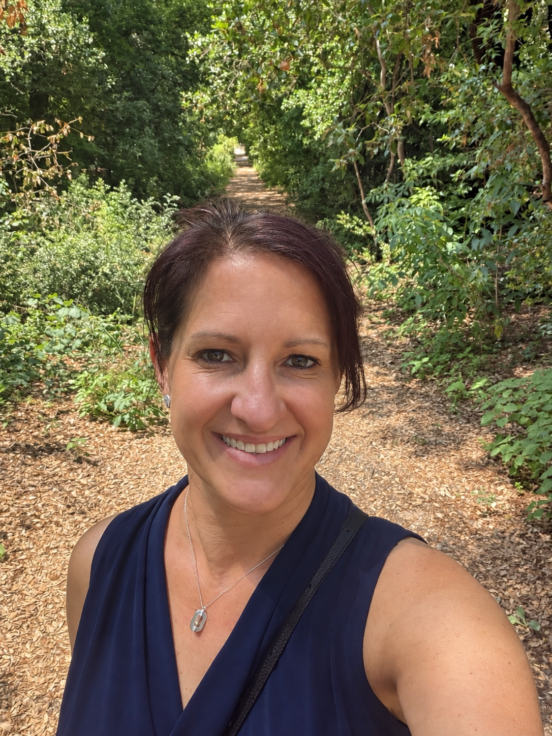 Christie smiling on a wooded path